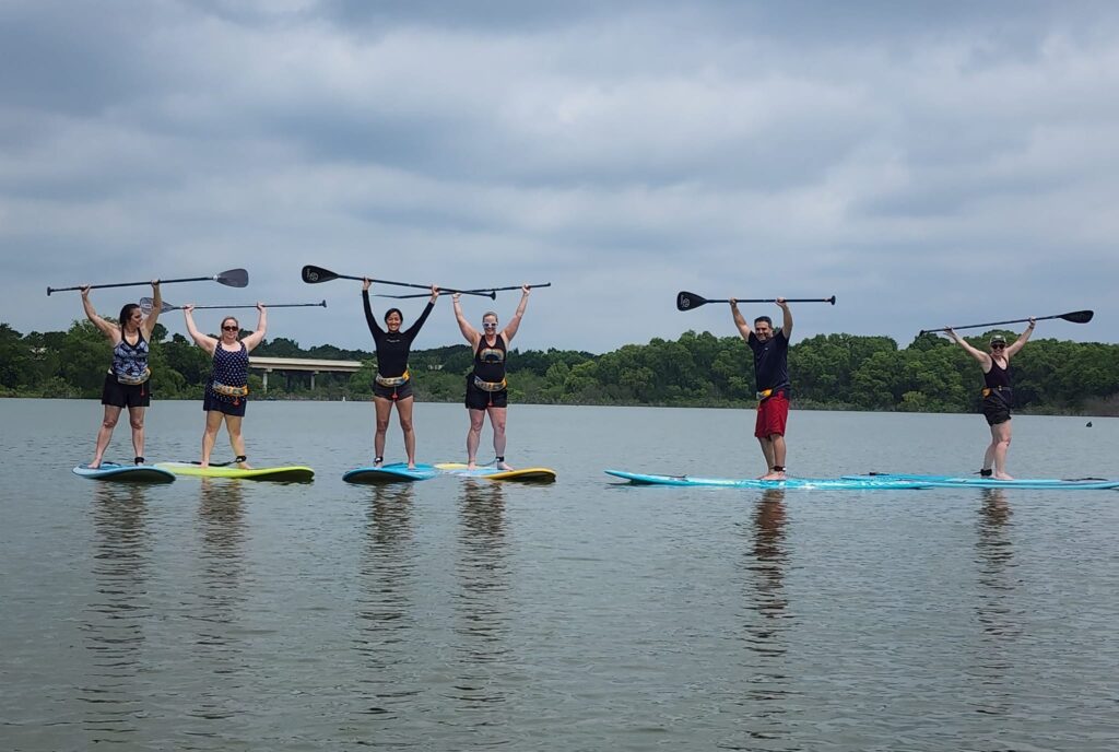 Paddle board class holding up their paddles on Lake Lewisville